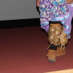 This lady is wearing a turtle shell rattle which was used in the dance. This lady is wearing a turtle shell rattle which was used in the dance.